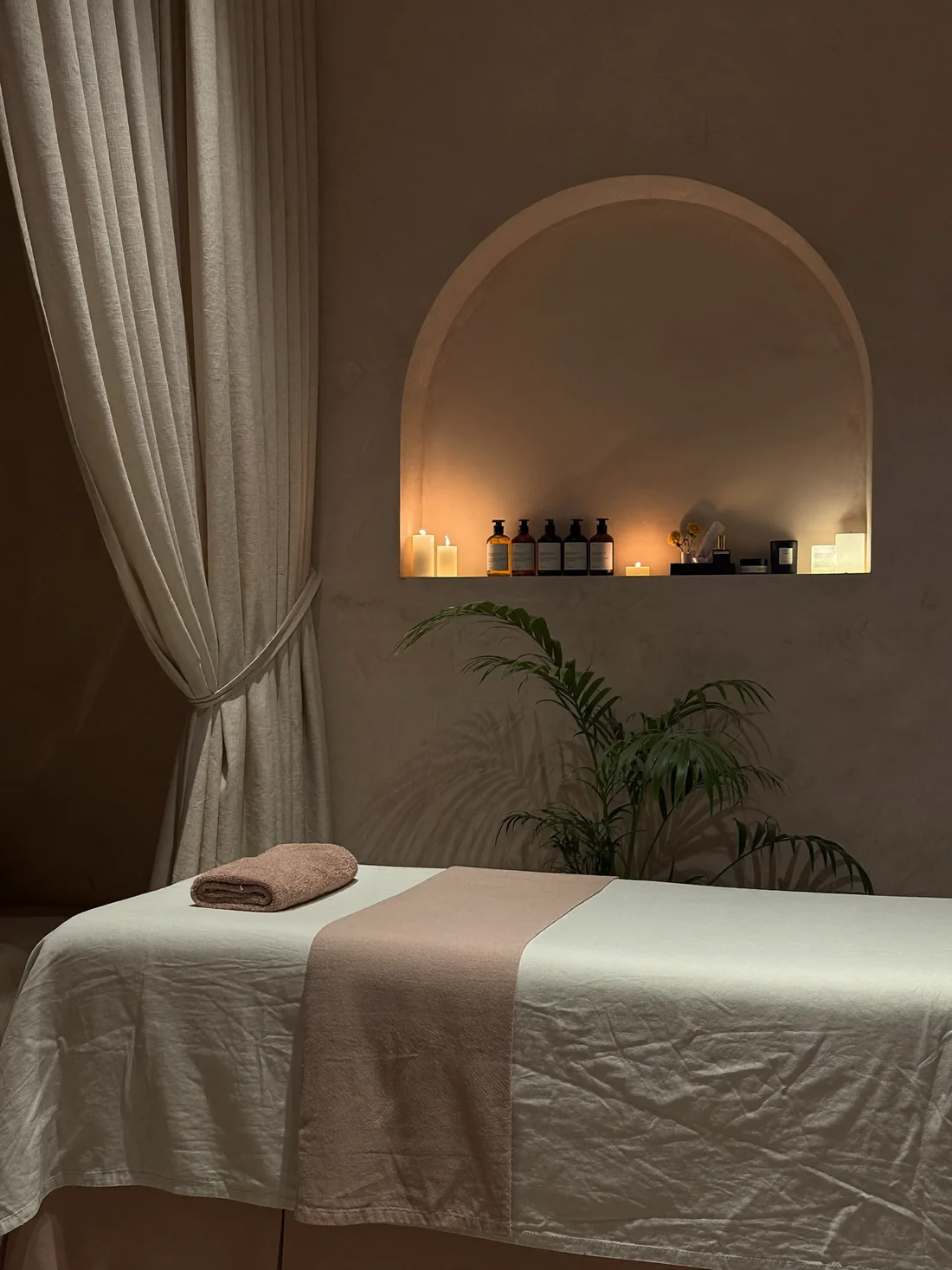 Cabine de soin Purelys en lin ivoire et rose poudré, bougies dans une niche en arche